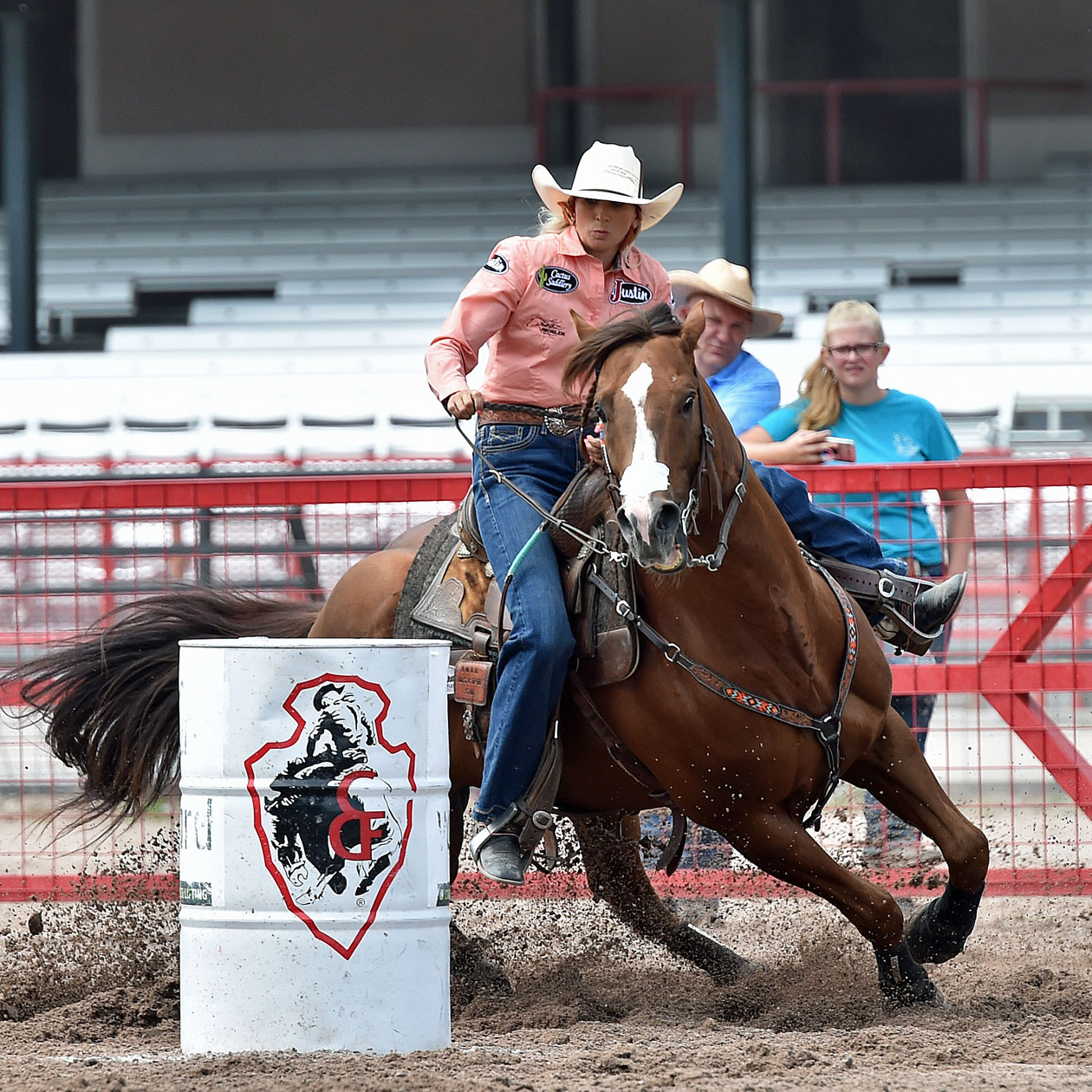 Women rides horse around barrel  